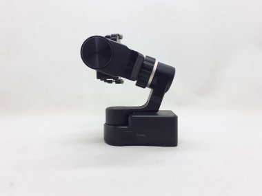 Beyaz izolasyon arka planında aksesuarları olan küçük siyah ve gri bir kamera.