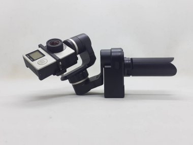 Beyaz izolasyon arka planında aksesuarları olan küçük siyah ve gri bir kamera.