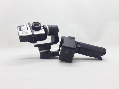 Beyaz izolasyon arka planında aksesuarları olan küçük siyah ve gri bir kamera.