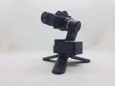 Beyaz izolasyon arka planında aksesuarları olan küçük siyah ve gri bir kamera.