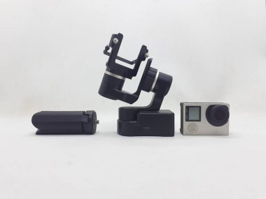 Beyaz izolasyon arka planında aksesuarları olan küçük siyah ve gri bir kamera.