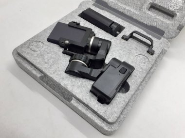 Beyaz izolasyon arka planında aksesuarları olan küçük siyah ve gri bir kamera.