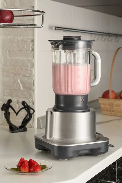 Mutfak masasında pişmiş çilekli smoothie ile blender. Böğürtlenli tabağın yanında..