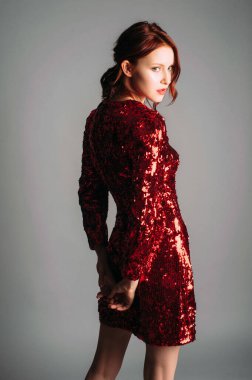 Kırmızı pullu elbise orta uzunlukta. Viraj modelinde ince, güzel bir elbise, çağdaş kadın parti arıyor. Kadın modası. 