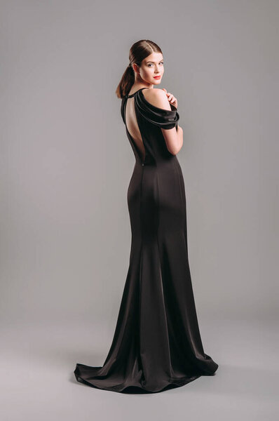 Black evening dress. Studio shot. Beautiful young woman in long sleeveless chiffon dress. 