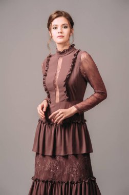 Klasik gece elbisesi. Zarif kahverengi elbise. Stüdyoda poz veren esmer kadın. Uzun kollu, fırfırlı, fırfırlı ve dantelli bohem tarzı bir kıyafet. Kadın cazibesi..