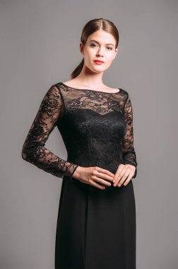 Tamamen siyah görünüş. Siyah dantelli trompet elbise. Uzun kollu akşam kıyafetleri. Kırmızı dudaklı, at kuyruğu saçlı güzel esmer bayan stüdyoda poz veriyor..