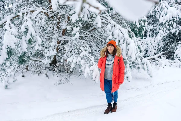 Mujer con una chaqueta y sombrero rojo cálido sobre un fondo de bosque nevado — Foto de Stock