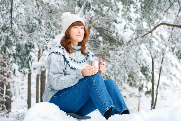 Mujer con una taza de té en las manos en medio de un bosque cubierto de nieve — Foto de Stock