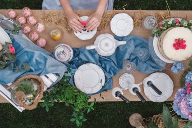 Tabaklar, çatal bıçaklar, bardaklar, mumlar ve çiçek düzenlemeleriyle süslenmiş köy usulü bir tatlı masası. Üst Manzara. Kopyala, metin için boşluk.