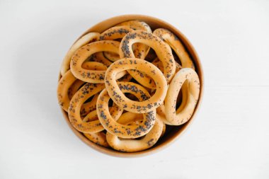 Beyaz arka planda tahta bir kasede haşhaş tohumlu kurutulmuş simit..