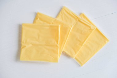 Beyaz ahşap masa arkasında ayrı paketlenmiş peynir dilimleri..