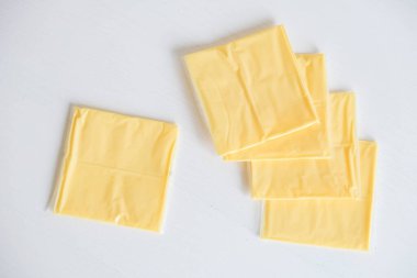 Beyaz ahşap masa arkasında ayrı paketlenmiş peynir dilimleri..