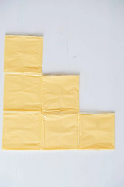 Separat verpackte Käsescheiben auf weißem Holztisch — Stockfoto
