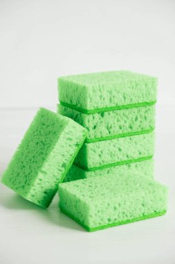 Beyaz arka planda temizlik için yeşil süngerler.