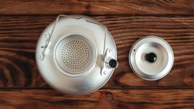 Ahşap masa arkasında yürüyüş yapmak için metal çaydanlık.