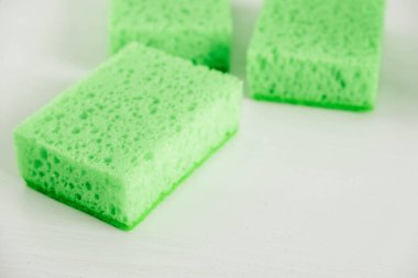 Beyaz arka planda temizlik için yeşil süngerler.