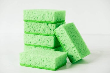 Beyaz arka planda temizlik için yeşil süngerler.