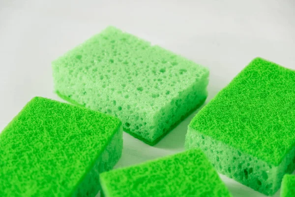 Green sponges for cleaning on a white background.