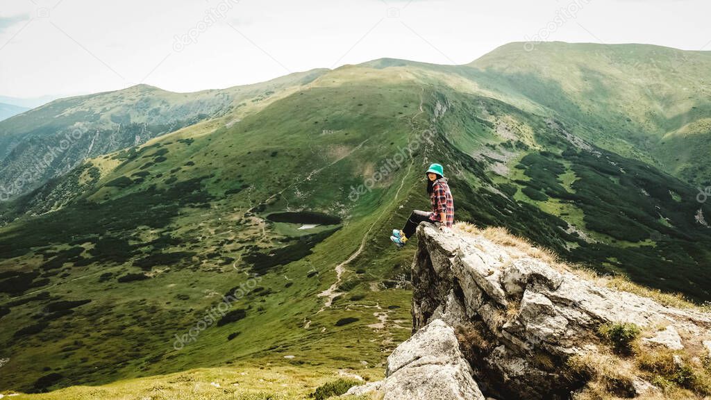 Woman tourist sitting on the background of green mountains and a lake.