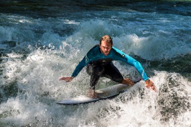Münih, Almanya - 13 Temmuz 2021: Münih şehir nehrinde sörfçü, Eisbach adı verilen kentsel çevrede sörf yapan insanlarla ünlüdür.