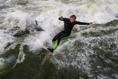 Münih, Almanya - 13 Ekim 2021: Münih şehir nehrinde sörfçü, Eisbach adı verilen kentsel çevrede sörf yapan insanlarla ünlüdür.