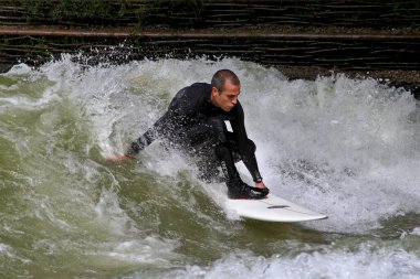 Münih, Almanya - 13 Temmuz 2021: Münih şehir nehrinde sörfçü, Eisbach adı verilen kentsel çevrede sörf yapan insanlarla ünlüdür.