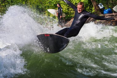 Münih, Almanya - 13 Temmuz 2021: Münih şehir nehrinde sörfçü, Eisbach adı verilen kentsel çevrede sörf yapan insanlarla ünlüdür.