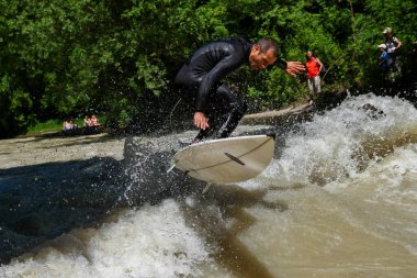 Münih, Almanya - 13 Temmuz 2021: Münih şehir nehrinde sörfçü, Eisbach adı verilen kentsel çevrede sörf yapan insanlarla ünlüdür.
