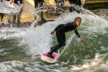 Münih, Almanya - 13 Temmuz 2021: Münih şehir nehrinde sörfçü, Eisbach adı verilen kentsel çevrede sörf yapan insanlarla ünlüdür.