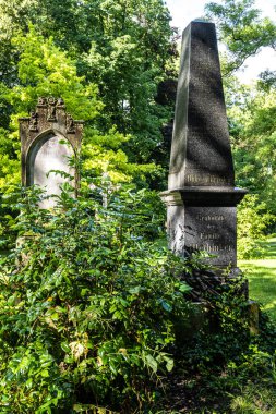 Münih, Almanya - Temmuz 09, 2021: Tarihi mezar taşlarıyla ünlü Münih Eski Kuzey Mezarlığı manzarası. Cenazeler 1944 'ten beri burada yapılmadı. Bunun yerine mezarlık bir park olarak kullanılıyor.