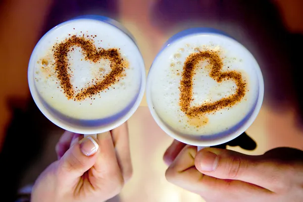 Goodmorning cup of coffee. 2 cups of coffee in hand and hearts are drawn on coffee foam. — Stock Photo, Image