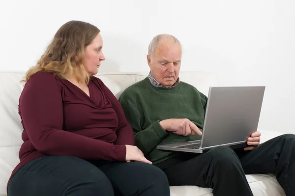 Jonge vrouw op laptop en gepensioneerden — Stockfoto