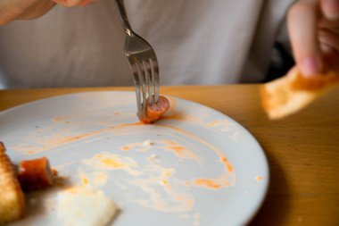 Bıçak ve çatallı bir kız İngiliz kahvaltısı yapar taze domatesler çırpılmış yumurta, çavdar ekmeği ve et sosisi yarın öğle yemeği