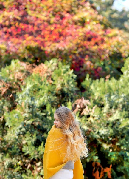公園を歩いている黄色の岬の若い白人の少女 背景は 秋の森の明るい葉です 気分と秋のコンセプト スペースのコピー — ストック写真