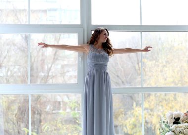 Pencerenin arka planında elbisesi olan çekici genç bir kız. Rahatla konsept