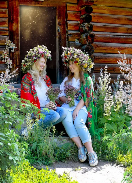 Щасливі Дівчата Дивляться Один Одного Великих Квіткових Вінках Плечах Сидять — стокове фото
