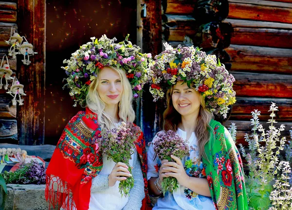 快乐的姑娘们 戴着大花环 肩上披着乌克兰国徽 坐着花束 农村木制房屋 乌克兰的传统 夏季概念 — 图库照片