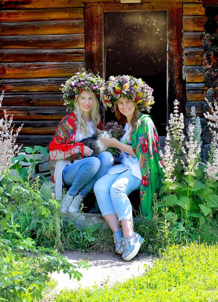 Две Девушки Больших Цветочных Венках Национальных Шарфах Плечах Сидят Кошкой — стоковое фото