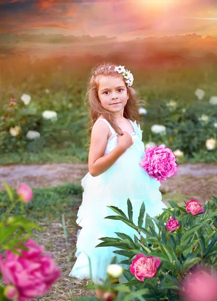 庭に大きなピンクの牡丹と風通しの良いミントの色のドレスでかわいい女の子 ボケ効果 夏のコンセプト — ストック写真