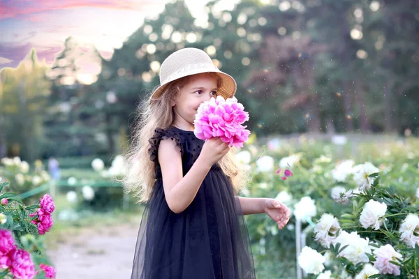 一个可爱的白人小女孩 身穿黑色衣服 头戴一顶粉色牡丹的帽子 靠近她的脸 花卉学概念 — 图库照片