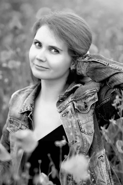 Mavi kot ceketli, şirin, kızıl saçlı genç bir kızın siyah beyaz portresi tarlada haşhaş kokusunun ve güzelliğinin tadını çıkarıyor. Güzellik ve moda konsepti.