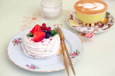 Çilek, böğürtlen, frenk üzümü ve bir fincan kapuçino ile süslenmiş tatlı kremalı tatlı. Şekerleme. Pişirme ve tatlı konsepti.