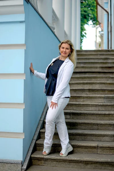 Счастливая Белая Женщина Белом Костюме Стоящая Лестнице Улыбающаяся Фон Синих — стоковое фото