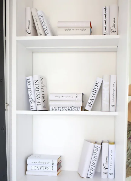 Shelves for books in the interior. White wooden bookcase in the living room. Scandinavian style. Modern interior and design concept
