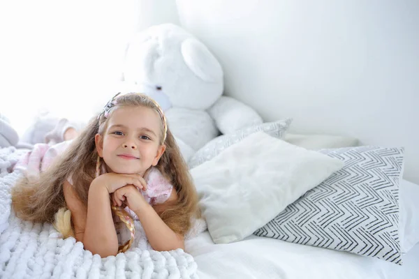 Banner with a little cute girl with a smile lies on the bed. Bright interior in the children's room. Scandinavian interior style. Childhood concept. Copy the space on the right