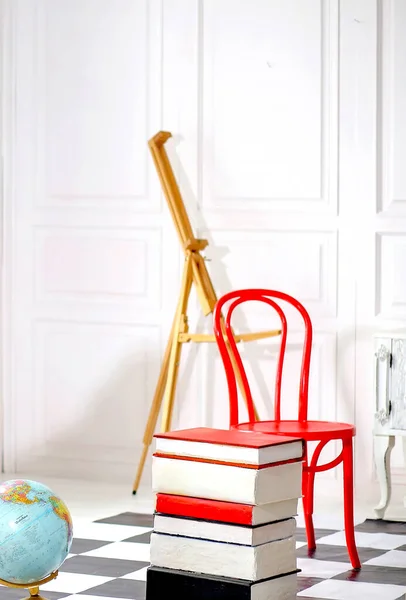 School supplies. A stack of books, a skateboard, a red backpack and an exercise table. Education concept.