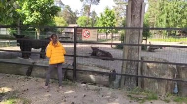 a little girl in a yellow raincoat is walking through the zoo