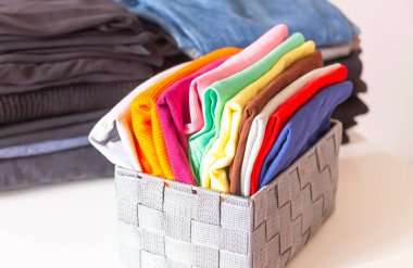 Kutuda katlanmış renkli kıyafetler var. Ev düzenleme. Ev içi dikey depolama.