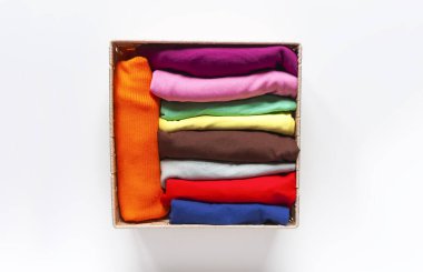 Kutuda katlanmış renkli kıyafetler var. Ev düzenleme. Ev içi dikey depolama.